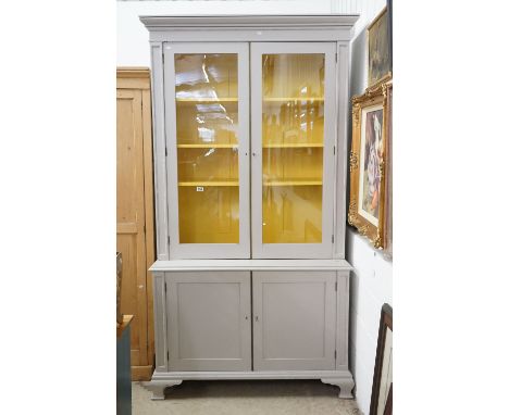 19th century Bookcase on Cupboard, later painted grey with a yellow interior, the upper section with two glazed doors opening