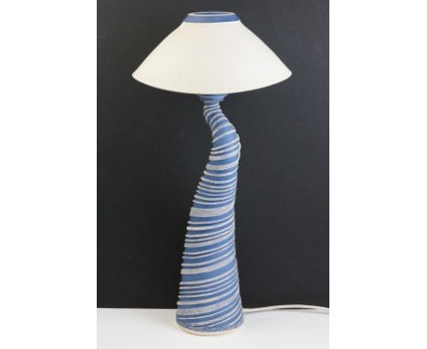 Ceramic pottery lamp base of spiralling shape having a blue ground with raised white detailing and ceramic shade to top. Mark