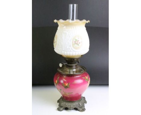 An antique oil lamp having floral decoration to base and opaque shade and scrolled feet. Measures approx 54cm high 