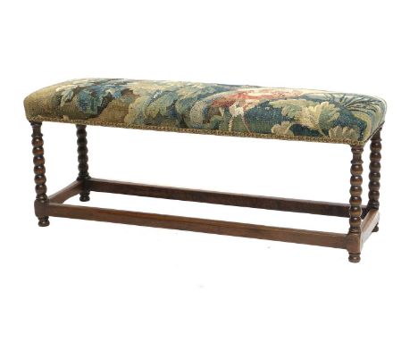 A French Walnut Double Stool, the top covered in a part fragment of a 17th century Flemish tapestry, with a close-nailed flor