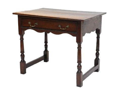 A George II Oak Side Table, mid 18th century, the boarded top above an oak-lined frieze drawer and wavy-shaped apron, on turn