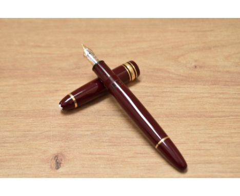 A boxed Mont Blanc Meisterstuck piston fill fountain pen in burgundy with gold trim having a 4810 14K Mont Blanc nib.