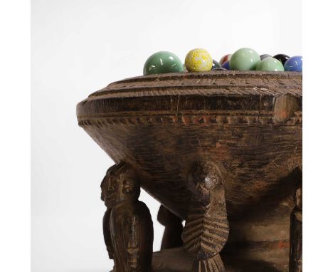 A carved divination bowl, mid-20th century, with a carved edge, raised on eight figures and a circular base, containing a qua