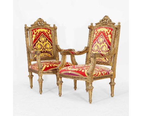 A pair of Louis XVI-style giltwood fauteuils, mid-20th century, Continental, each with a pierced floral crest and open arms, 