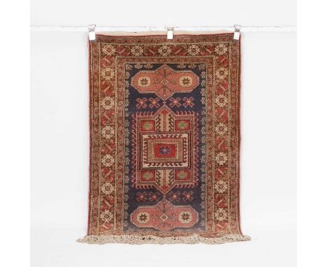 A wool rug, 20th century, Caucasian, the central field with three geometric motifs on a navy ground, within multiple foliate 