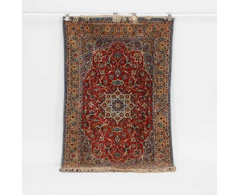 A wool carpet, 20th century, Persian, the central red field with a cream medallion, within multiple foliate borders, 105 x 70