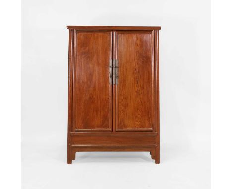 A hardwood cabinet, Qing dynasty (1644-1911), Chinese, of tapering form, with a moulded top, over two cupboard doors with loo