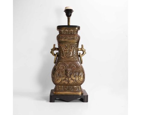 An archaic-style brass lamp, 20th century, Chinese, with a pair of ring handles, and decorated with stylised scrolls and mask