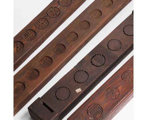 A group of four carved wood rice cake moulds, 19th century, Korean, carved with calligraphy and foliage, 53cm wide6cm deep3.5