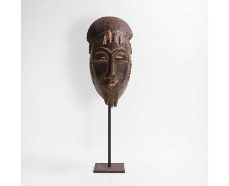 A carved mask, 20th century, Côte d'Ivoire, Baule people, with remnants of a carved woven beard, with a later metal stand, 18