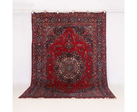 A wool carpet, of recent manufacture, the red ground with a navy and cream medallion, the spandrels similarly decorated, 307 