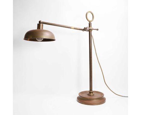 A brass table lamp, 20th century, with an adjustable support and fitted with a dome shade, raised on a dished circular base,2