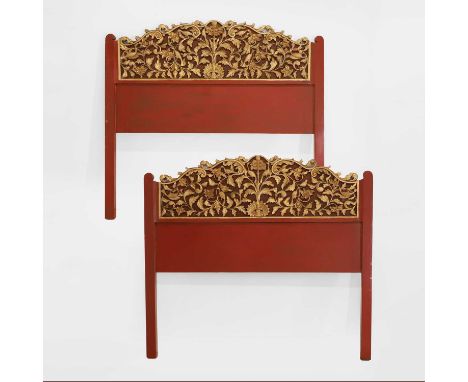 A pair of carved, gilt and lacquered headboards, each with shaped and scrolled blind fretwork with birds, on red-lacquered pa