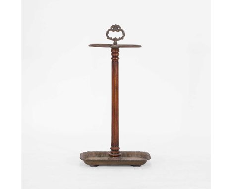A walnut and brass stick stand, 19th century, with a scrolling loop handle and four divisions, above a reeded column and a le