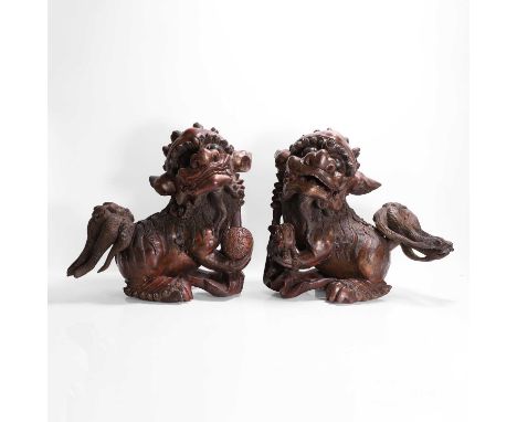 A pair of gilt-lacquered wood carvings, late Qing dynasty, Chinese, of a pair of Buddhist lions, both seated on their haunche