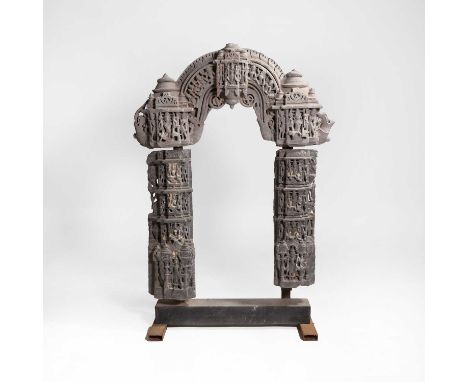 A carved stone arch, 12th century, Indian, Rajasthan, formed in three sections, each with a central deity seated in a columna