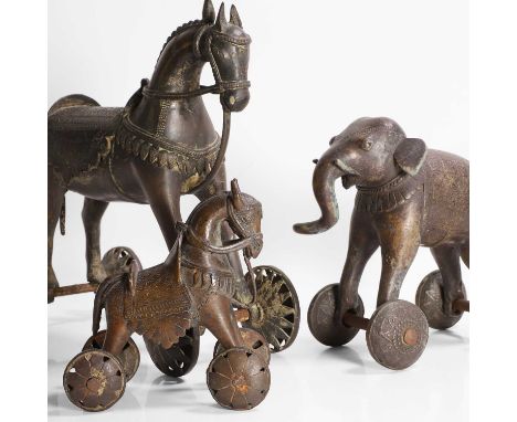 A brass alloy temple horse, late 19th/early 20th century, Indian, mounted with saddle and bridle, raised on pierced convex wh