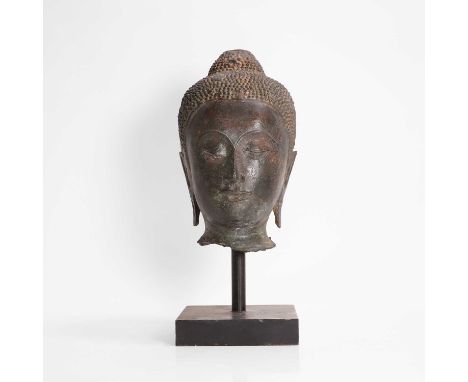A bronze head of Buddha, possibly 17th/18th century, Thai, cast with his hair in tight curls with a topknot, with elongated e