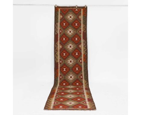A kilim runner, the central field with an alternating diamond design,379 x 87cm
