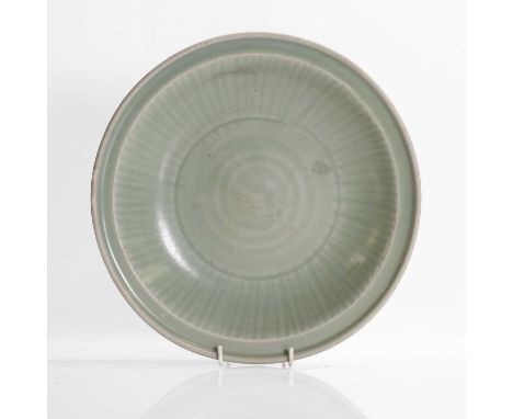 A Longquan ware plate, Ming dynasty (1368-1644), Chinese, the shallow, heavily potted sides, rising from a short tapering foo