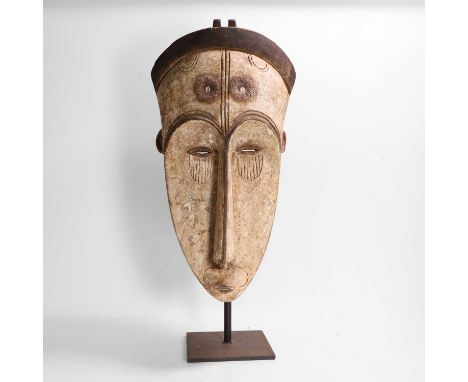A large painted Ngil-type mask, 20th century, Gabon, Fang people, the large forehead inset with cowrie shells, above an elong