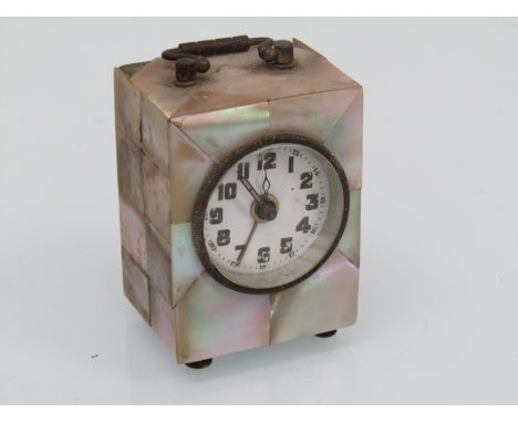 An early 20th Century mother of pearl cased miniature alarm clock, 7cm high, two case veneer pieces missing at top back corne