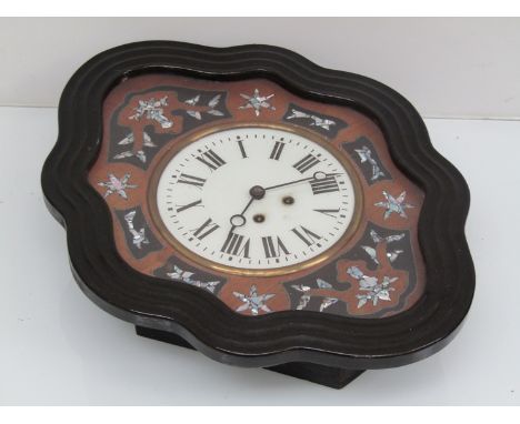 A late 19th/ early 20th Century French ebonised dial clock of shaped form, the bezel surrounded by mixed hardwood and mother 