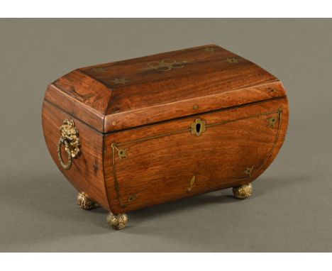 A Regency rosewood brass strung sarcophagus shaped tea caddy, with lidded interior, brass fittings and brass ball feet.  Widt