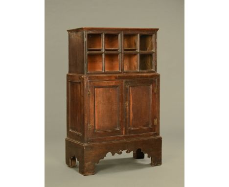 An early 18th century oak glazed bookcase (circa 1730), with cupboard base raised on tall bracket feet and the upper section 