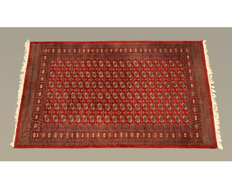 An Indian Bokhara silky pile rug, the centre rectangular panel with multiple repeating design and with multiple line border, 