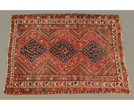 An Eastern fringed rug, the centre rectangular panel with three diamond shaped motifs and with repeating line border, princip