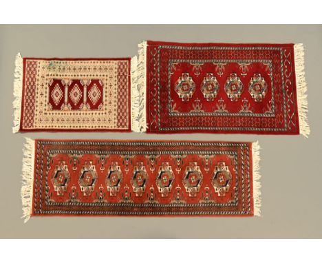 An Eastern runner and two fringed rugs, the largest with seven repeating designs to the rectangular panel and with multiple l