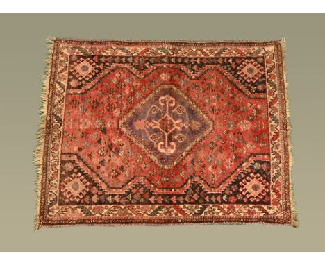 An Eastern fringed rug, with centre rectangular panel, principal colours red, blue, brown and beige.  153 cm x 122 cm.