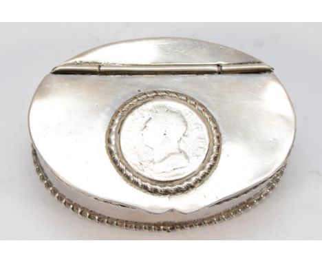 An unmarked white metal oval snuff box, the hinged lid inset with a George IV coin, gadrooned border, 7.5 x 5.5 x 2cm. 