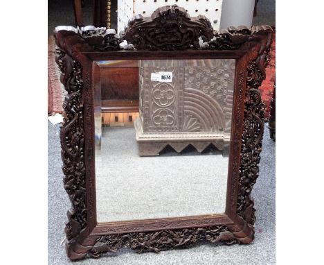 A Chinese hardwood mirror with extensively carved frame depicting hunting scenes, dragons and wildlife, 50cm wide x 64cm high