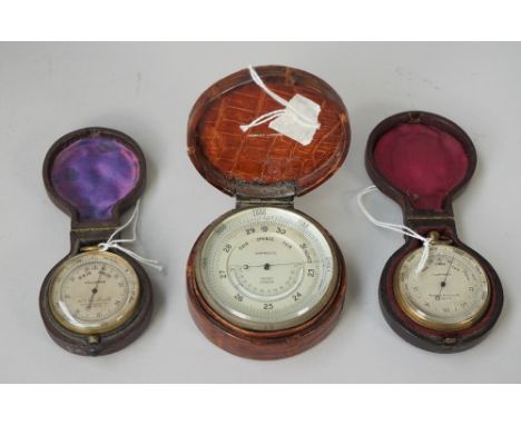 An Asprey brass cased table barometer, circa 1900, with thermometer compendium in a crocodile skin case (7cm diameter), a Sho