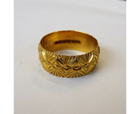 A 22ct gold wide band wedding ring, with facet cast decoration, London 1973, ring size Q and a half, weight 7 gms.