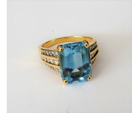 A gold, blue topaz and diamond ring, claw set with the cut cornered rectangular blue topaz to the centre, the shoulders mount