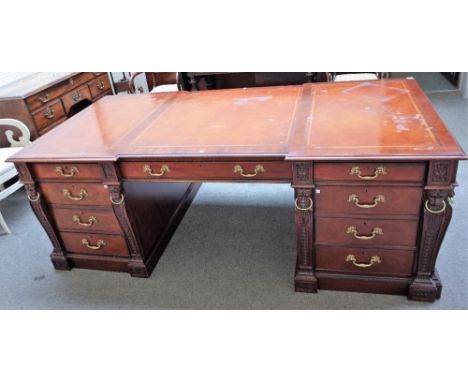 After Chippendale, a modern mahogany pedestal desk with nine frieze drawers and opposing cupboards, mounted with lions' head 