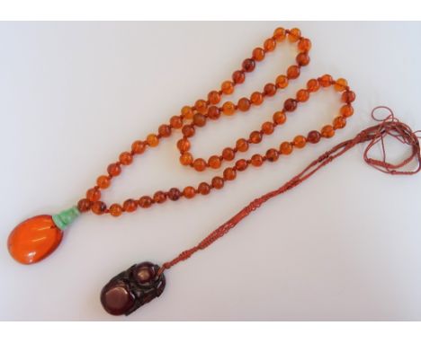 An Asian amber and jade pendant necklace, the front with an oval amber drop, with a jade surmount, fitted to a translucent va
