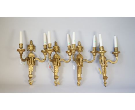 A set of four Louis XVI style ormolu twin light wall appliques, early 20th century, each cast with flaming urn finials over a