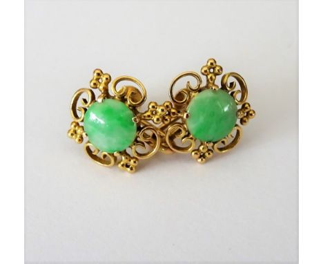 A pair of gold and jade earrings, each mounted with a circular jade within a scroll pierced and beaded surround, the backs wi