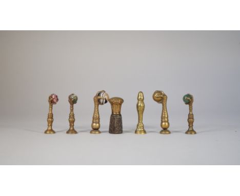 Four late 19th century brass seals, each cast with a claw clutching a hardstone ball, a similar solid brass version, another 