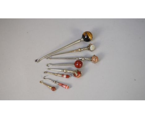 A miniature silver button hook with a striated agate handle (6cm), another similar, five larger white metal button hooks each