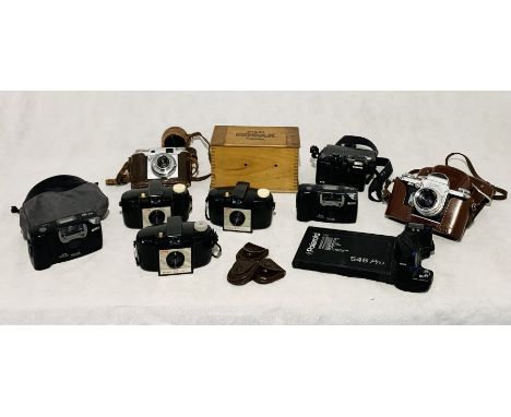 A collection of various cameras and equipment including a Kodak model B developing tank, three Brownie 127, Acon 35 model 11 