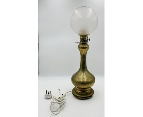 A vintage brass oil lamp with etched detail to base and round glass shade 
