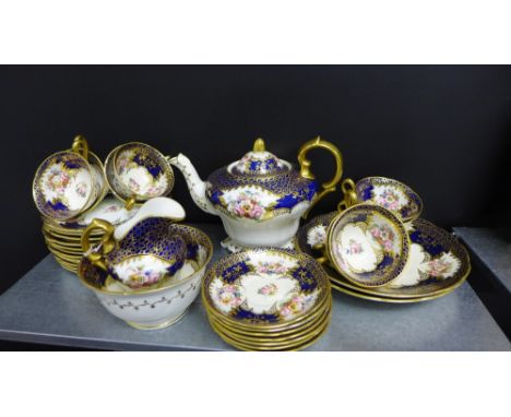 A late 19th century porcelain tea set painted with floral sprays against a cobalt and gilt ground comprising tea pot, milk an