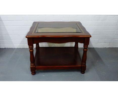 A mahogany and glass topped two tier lamp table on turned column supports