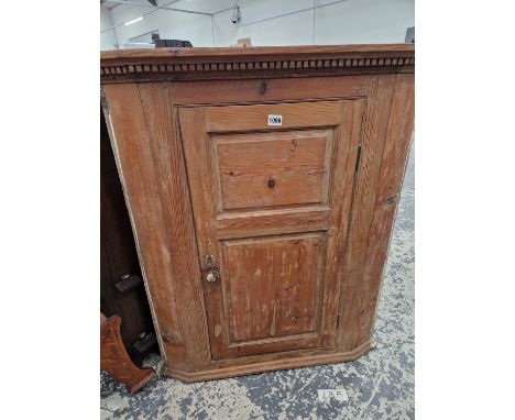 A 19TH CENTURY PINE CORNER CABINET WITH FIELDED PANEL DOOR.