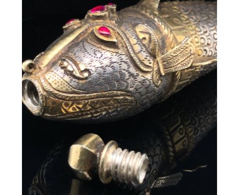 A 19th CENTURY EASTERN GILDED SILVER ARTICULATED FISH FORM POWDER FLASK. THE ANTHROPOMORPHISED HEAD INSET WITH RED CABOCHONS 